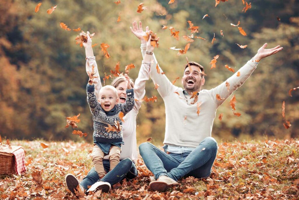 Familie wirft Herbstblätter in die Luft