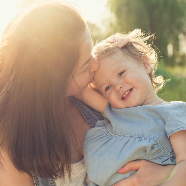 Mutter küsst ihrer Tochter auf die Stirn